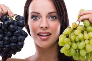 woman holding red and green grapes