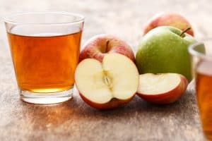 Glass of apple juice with apples on the table