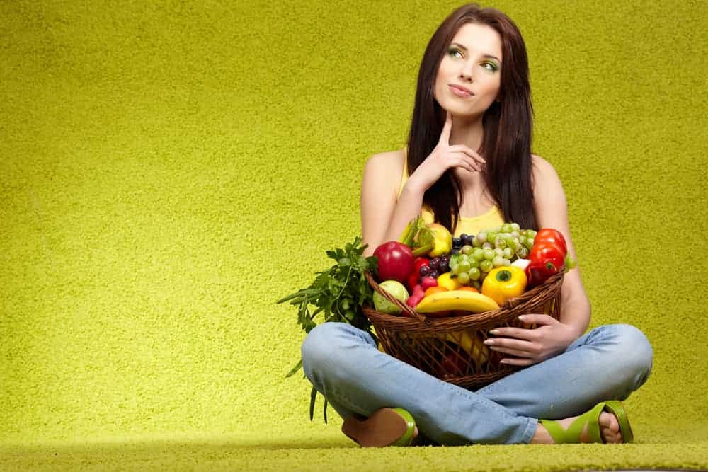 woman holding basket of healthy fruit and vegetables