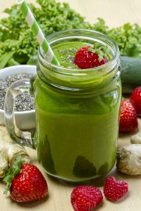 healthy green juice surrounded by fruit and vegetables