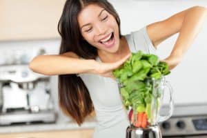 Woman juicing leafy green vegetables