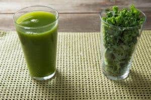 glass of kale juice and kale leaves in second glass