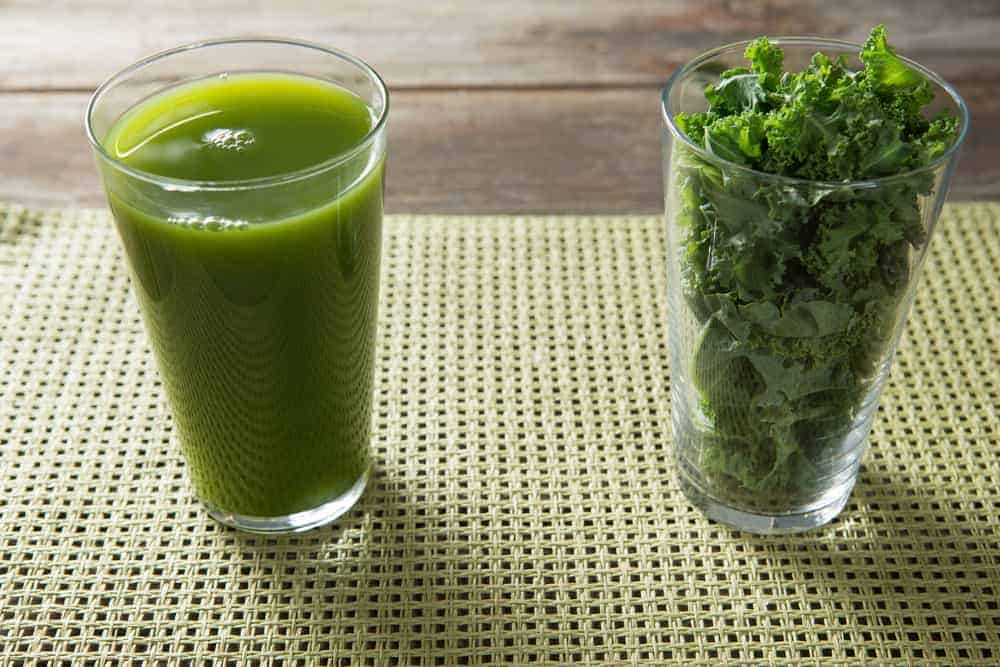 glass of kale juice and kale leaves in second glass