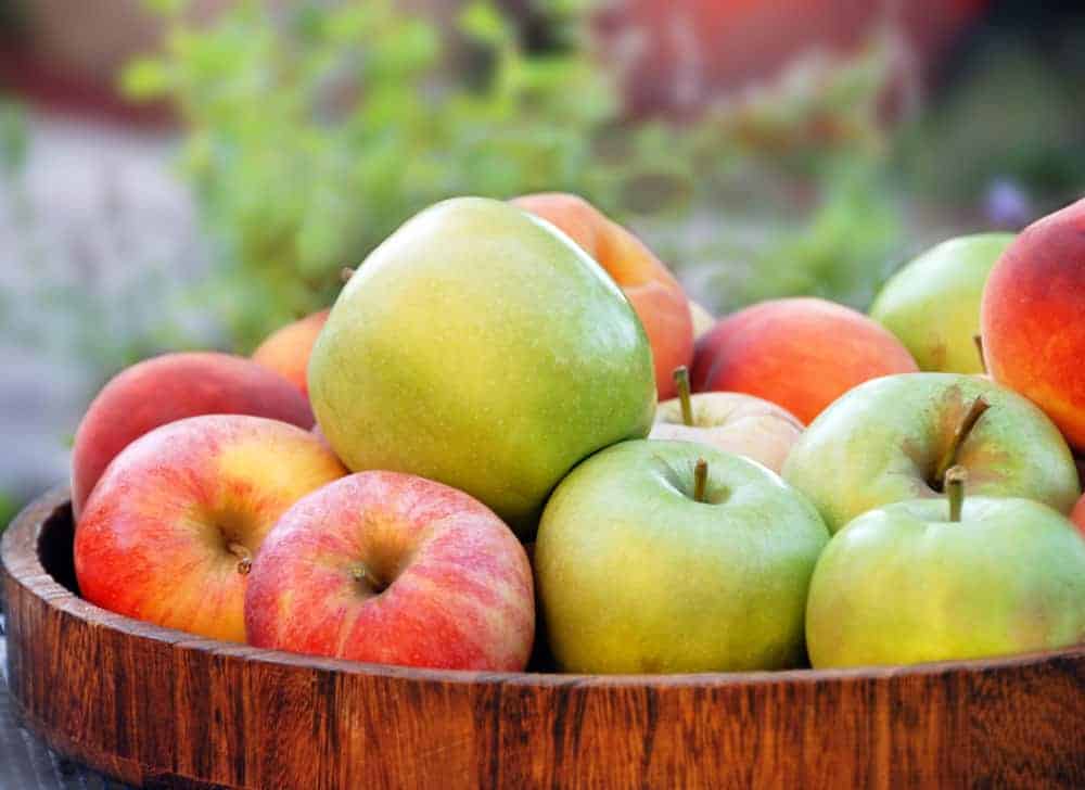 red and green apples in a wooden dish