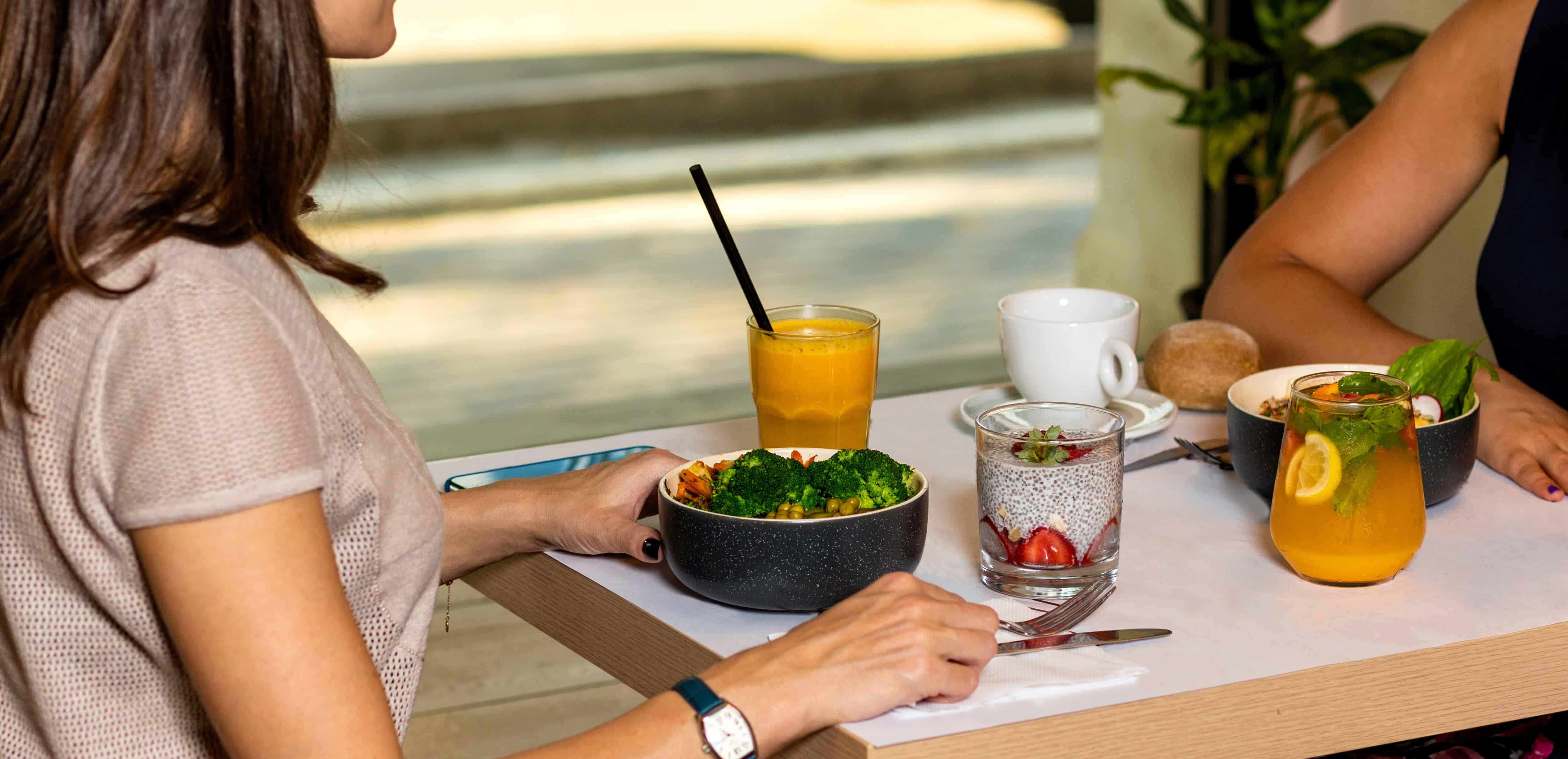 two people having juice and food on a wooden table 